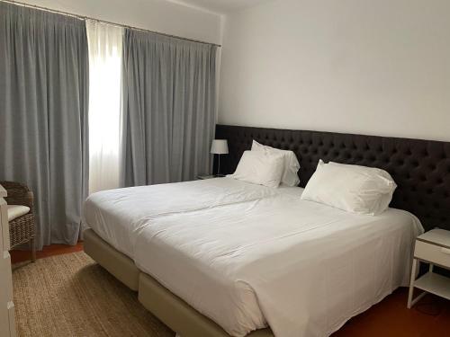 sypialnia z dużym łóżkiem z białą pościelą i poduszkami w obiekcie Quinta do lago & golf w mieście Quinta do Lago