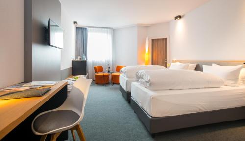 a hotel room with two beds and a desk at IntercityHotel Bremen in Bremen