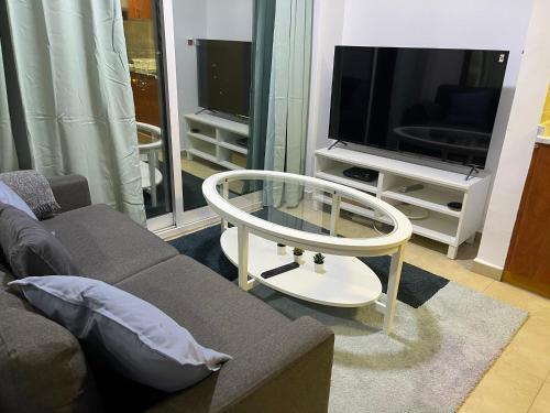 a living room with a couch and a table and a tv at Near Metro - Lovely Modern 1 Bedroom in JLT in Dubai