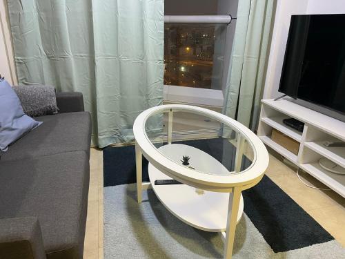 a white round table in a living room with a tv at Near Metro - Lovely Modern 1 Bedroom in JLT in Dubai