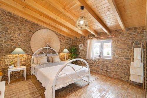 1 dormitorio con cama y pared de piedra en Quinta do Silêncio, en Tavira
