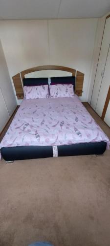 a bed in a small room with a pink comforter at Springs 46 by Vilija Southview Leisure Park Skegness in Skegness