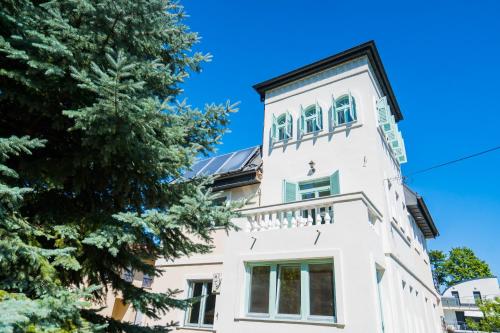 a white building with a tree in front of it at Harmony Boutique Villa in Siófok