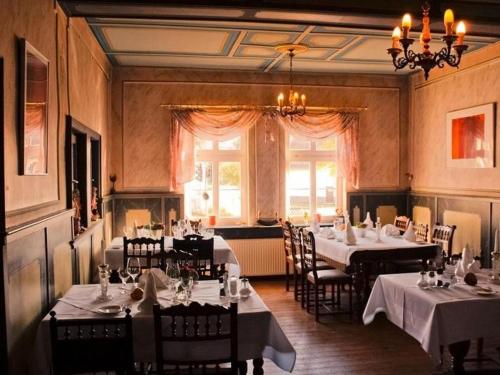 Ehlener Poststuben في Habichtswald: غرفة طعام بها طاولات وكراسي وثريا