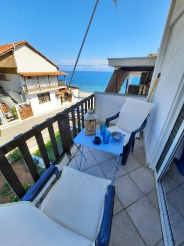 un balcón con 2 sillas, una mesa y el océano en Beautiful Seaside Studio, en Akráta
