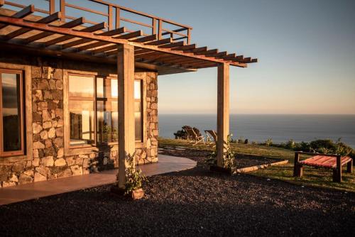 a stone house with a pergola next to the ocean at Villa - Cantinho do Paraíso in Santo Espírito
