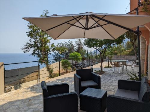un patio avec une table, des chaises et un parasol dans l'établissement Appartement Villa Belle Epoque Roquebrune Cap Martin, à Roquebrune-Cap-Martin