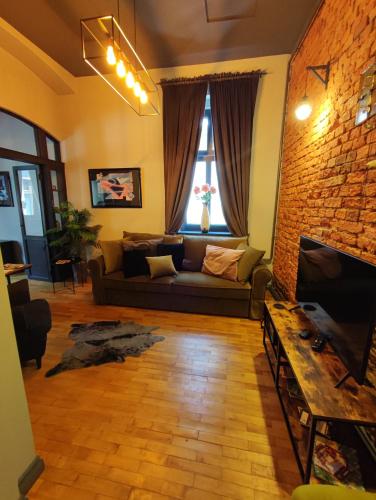 a living room with a couch and a brick wall at Apartament Podcienie z tarasem Bielsko-Biała Old Town in Bielsko-Biala