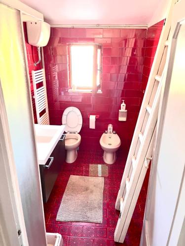 a red bathroom with a white toilet and a sink at Garden house in Bolsena