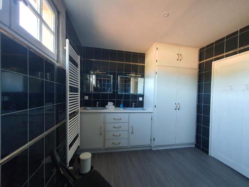 baño con armarios blancos y paredes de azulejos negros en Le Pressoir de Marsac en Marsac