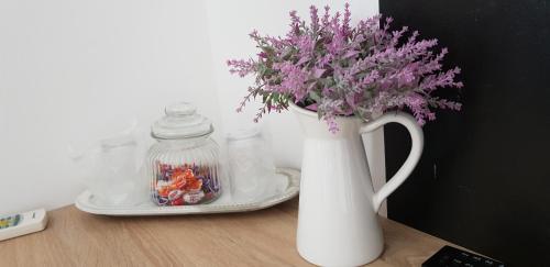 a white vase with purple flowers on a table at Sîrbu Orsova in Orşova