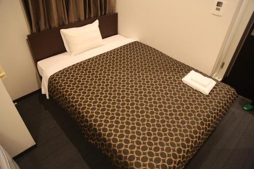 a bedroom with a bed with a brown comforter at Hotel Excellence Kyoto Ekimae in Kyoto