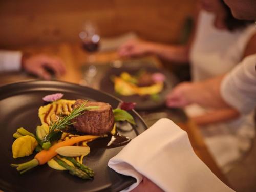 a person holding a plate of food on a table at Sporthotel Wagrain in Wagrain