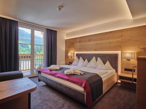 a bedroom with a large bed and a large window at Sporthotel Wagrain in Wagrain