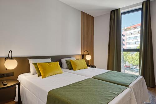 a bedroom with a large bed with yellow and green pillows at DWO Colours Alcalá in Madrid