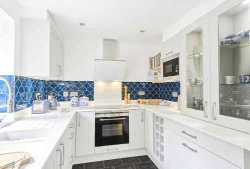 una cucina con armadi bianchi e piastrelle blu di Hope Cottage a Bridport
