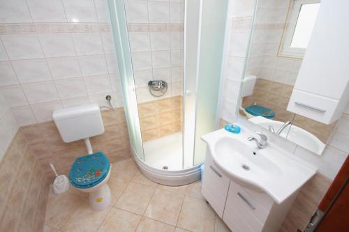 uma casa de banho com um chuveiro, um WC e um lavatório. em Apartment Njivice 5458a em Njivice