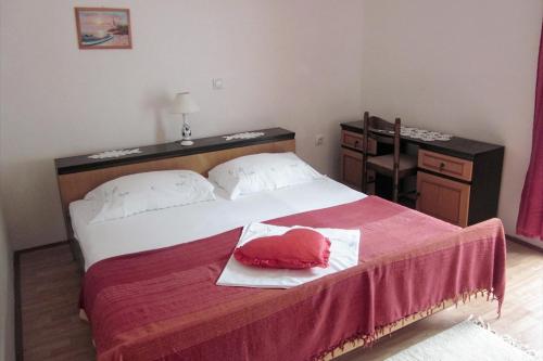 a bedroom with a bed with a red pillow on it at Family friendly apartments with a swimming pool Mundanije, Rab - 5076 in Rab