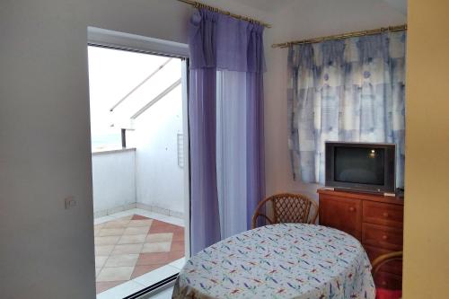 a room with a tv and a table and a window at Apartment Njivice 5458c in Njivice