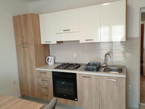cocina con armarios blancos, fogones y fregadero en Apartments and rooms with parking space Metajna, Pag - 4120, en Metajna