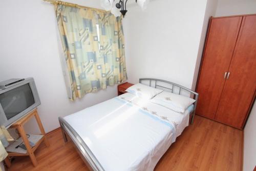 a small bedroom with a bed and a tv at Apartment Njivice 5458d in Njivice
