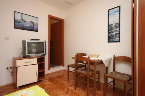 a living room with a table and a television at Studio Drvenik Donja vala 6658a in Drvenik