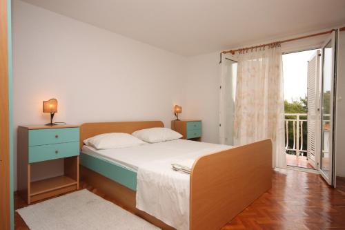 Apartments by the sea Drvenik Donja vala, Makarska - 6658 في درفينيك: غرفة نوم بسرير ونافذة كبيرة