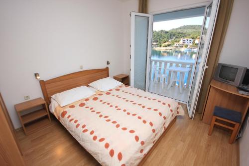 Schlafzimmer mit einem Bett und einem Balkon mit einem TV in der Unterkunft Double Room Zaglav 8144a in Zaglav