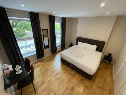 1 dormitorio con cama blanca y suelo de madera en George Canning Denmark Hill, London en Londres