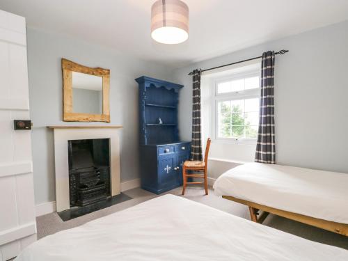 a bedroom with two beds and a fireplace at Roanview Cottage in Askam in Furness