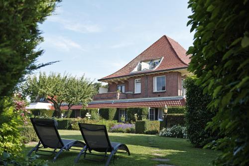 two chairs sitting in the grass in front of a house at Villa Magnolia in Oostkapelle
