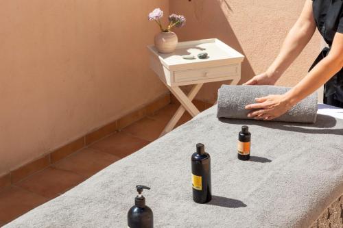a woman standing next to a table with three bottles on it at Hôtel Les Mouettes - Teritoria in Ajaccio