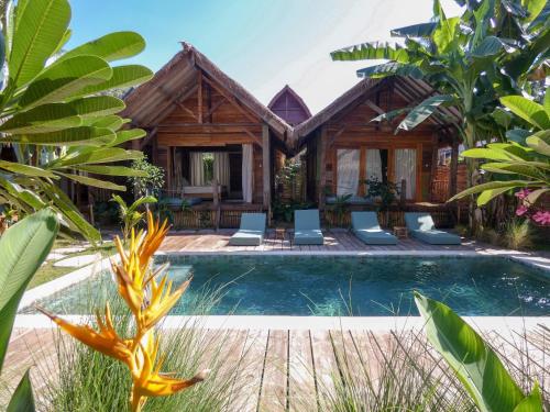 a villa with a pool in front of a house at La Siesta bungalows & Cuisine in Gili Air