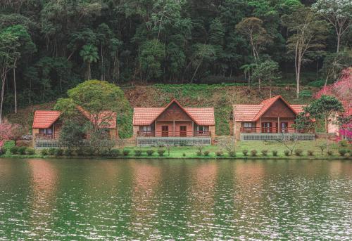 a row of houses on the shore of a lake at Natureza Eco Lodge in Vargem Alta