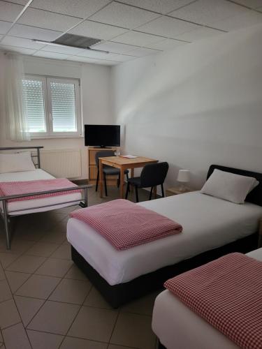 a room with two beds and a table and a desk at Guest House Talas in Osijek
