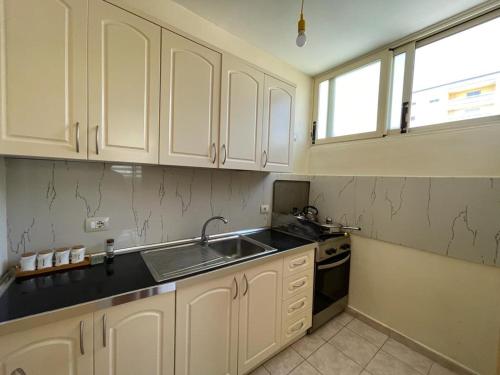 發羅拉的住宿－Lisus Apartment，厨房配有白色橱柜、水槽和窗户。