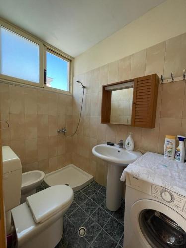 un bagno con un lavandino del water e una lavatrice di Lisus Apartment a Vlorë