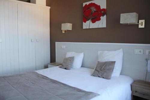 a bedroom with a large white bed with two pillows at Hôtel L'Escale Blanche in Les Orres