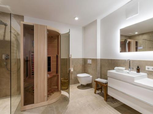 La salle de bains est pourvue de toilettes, d'un lavabo et d'une douche. dans l'établissement Apartment Hideaway - Stylisch, ruhig, Topausstattung, Infrarotsauna, Dachterrasse, à Walchsee