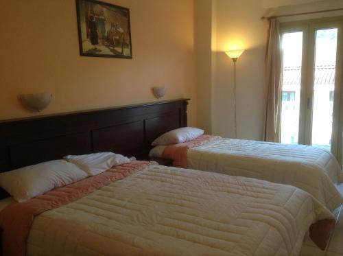 a hotel room with two beds and a window at Hotel Kosta Famissi in Kalabaka
