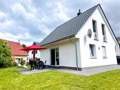 a white house with a red umbrella in the yard at Ferien-VILLA VIVA LA VIDA in Göhren-Lebbin
