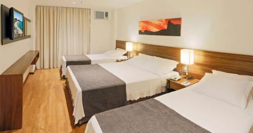 a hotel room with two beds and a television at Premier Copacabana Hotel in Rio de Janeiro