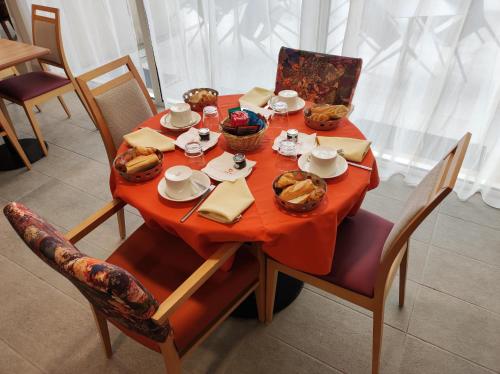 een tafel met een rode tafelkleed en voedsel erop bij Domitys Le Jardin des Lys in Alençon