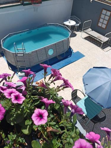 a hot tub with purple flowers and an umbrella at Alojamento local Angel`s in Ponte da Barca