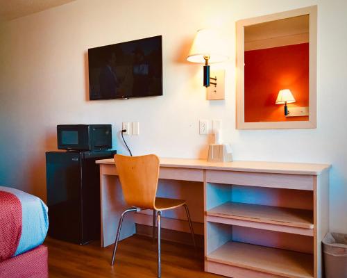 a room with a desk with a chair and a mirror at Travelodge by Wyndham Madison Heights MI in Madison Heights