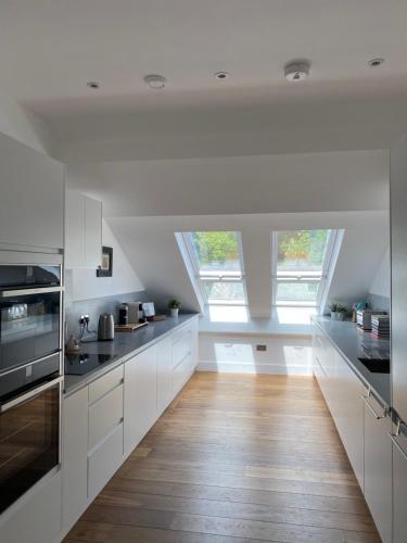 een keuken met witte kasten en een houten vloer bij Springfield Court 12 in Harrogate