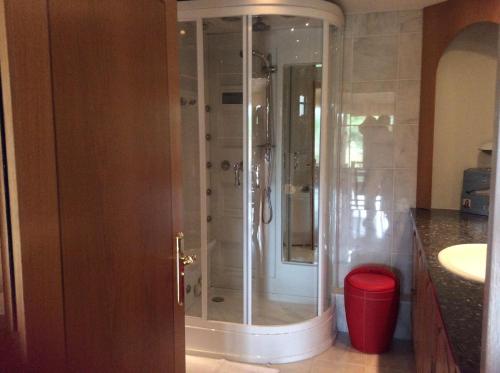a bathroom with a shower and a red trash can at Room in Apartment - Luxury Apartment Lily Suite in Truro