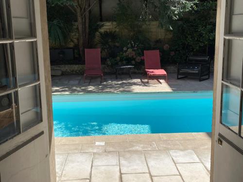a view of a pool with two chairs and a table at La Maison aux murs anciens et ses chambres in Tarbes