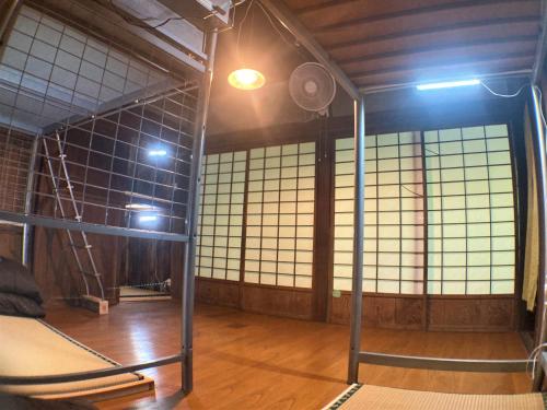 een kamer met een stapelbed en een aantal ramen bij ゲストハウス大安吉田 in Matsuzaki