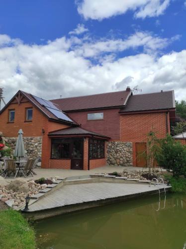 a house with a dock in front of a body of water at Poilsio namelis Plateliai in Plateliai